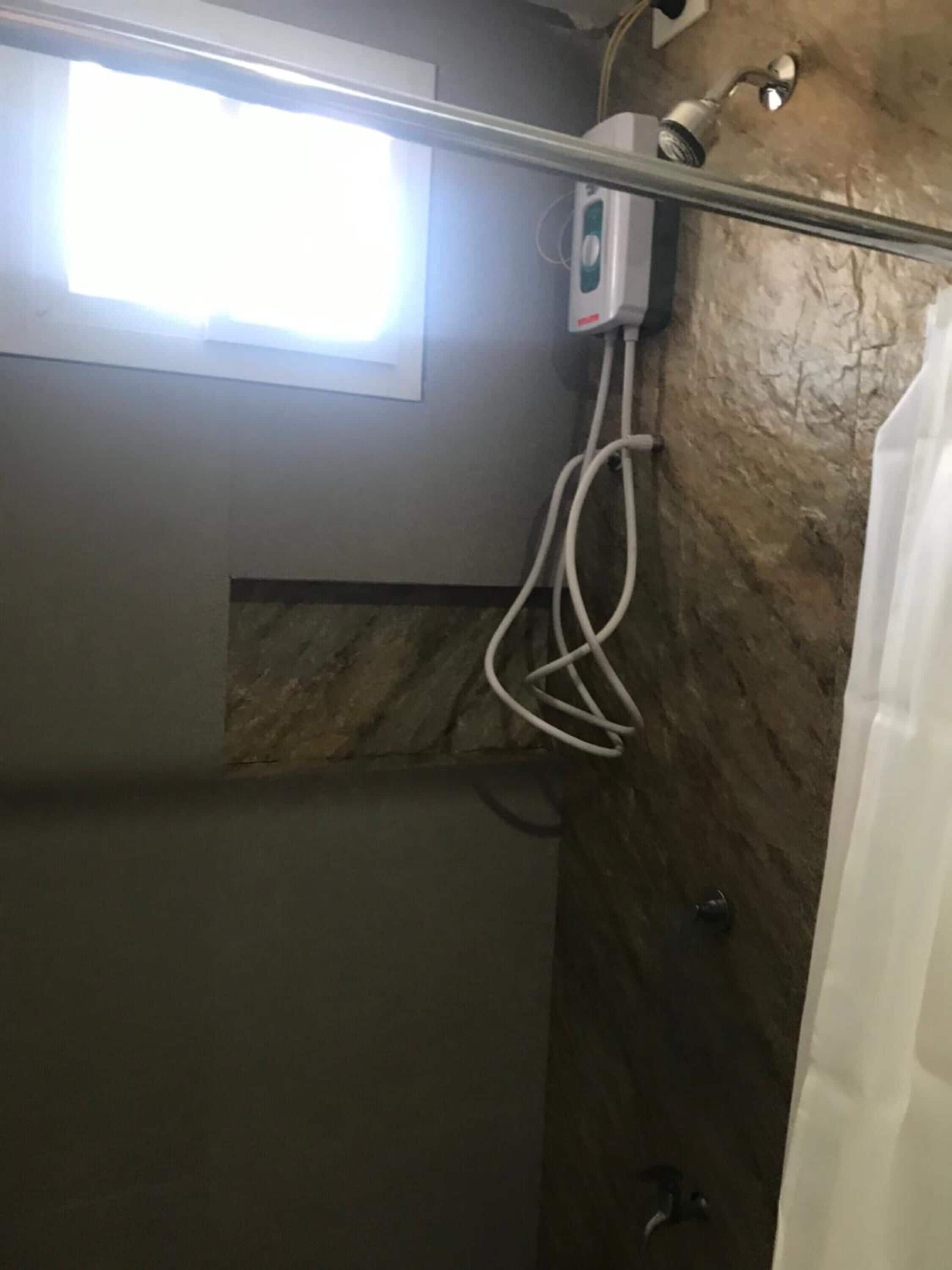 Un área de ducha con ventana, un perchero y un cabezal de ducha.