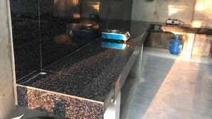 A kitchen with a black granite countertop, a blue gas cylinder, and a 'No Smoking' sign on the wall. - Seabreeze Beach Lodge (Nasugbu)