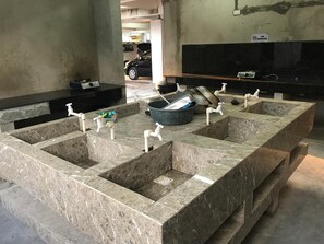 A public restroom with marble sinks and faucets, a trash bin, and a 'No Smoking' sign. - Seabreeze Beach Lodge (Nasugbu)