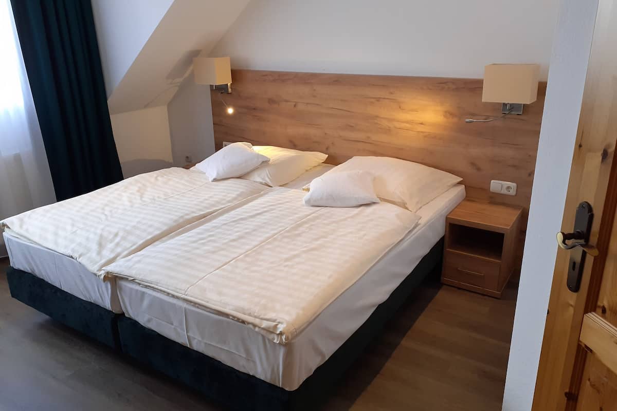 Ein Doppelbett mit Holzüberbau, zwei Nachttische mit Lampen und ein kleiner Holznachtschrank.