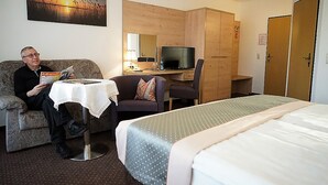 Ein Hotelzimmer mit einem Bett, einem Schreibtisch mit Computer, einem Fernseher und einem Sofa.