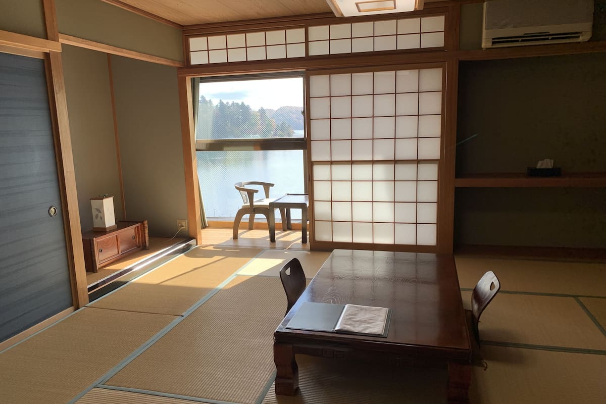 A traditional Japanese room with tatami flooring, a low table, and sliding shoji doors.