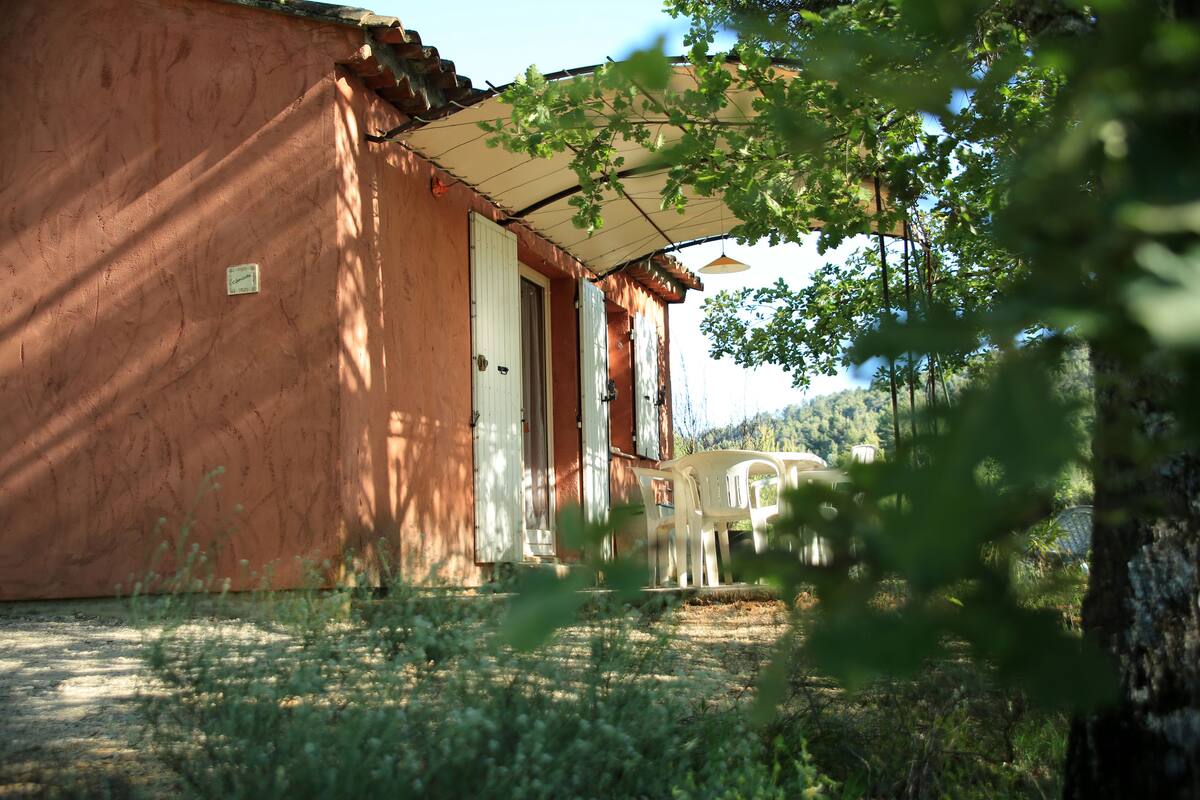 Un edificio rústico de madera con un porche cubierto y una puerta blanca.