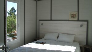 Een slaapkamer met een bed, een raam en een plafondlamp.