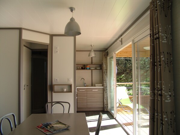 A modern kitchen with a dining area, a built-in oven, and a window overlooking a garden.
