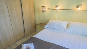 A hotel room with a bed, a nightstand, and a wall-mounted light fixture. - COLLINE DU CHATEAU AP4077 by RIVIERA HOLIDAY HOMES (Niza)
