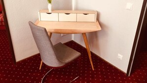 A corner desk with a chair, a vase with flowers, and a patterned carpet. - Gästehaus Albers (Cochem)