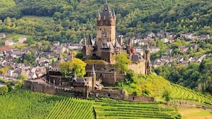 A historic castle surrounded by lush greenery and vineyards. - Gästehaus Albers (Cochem)