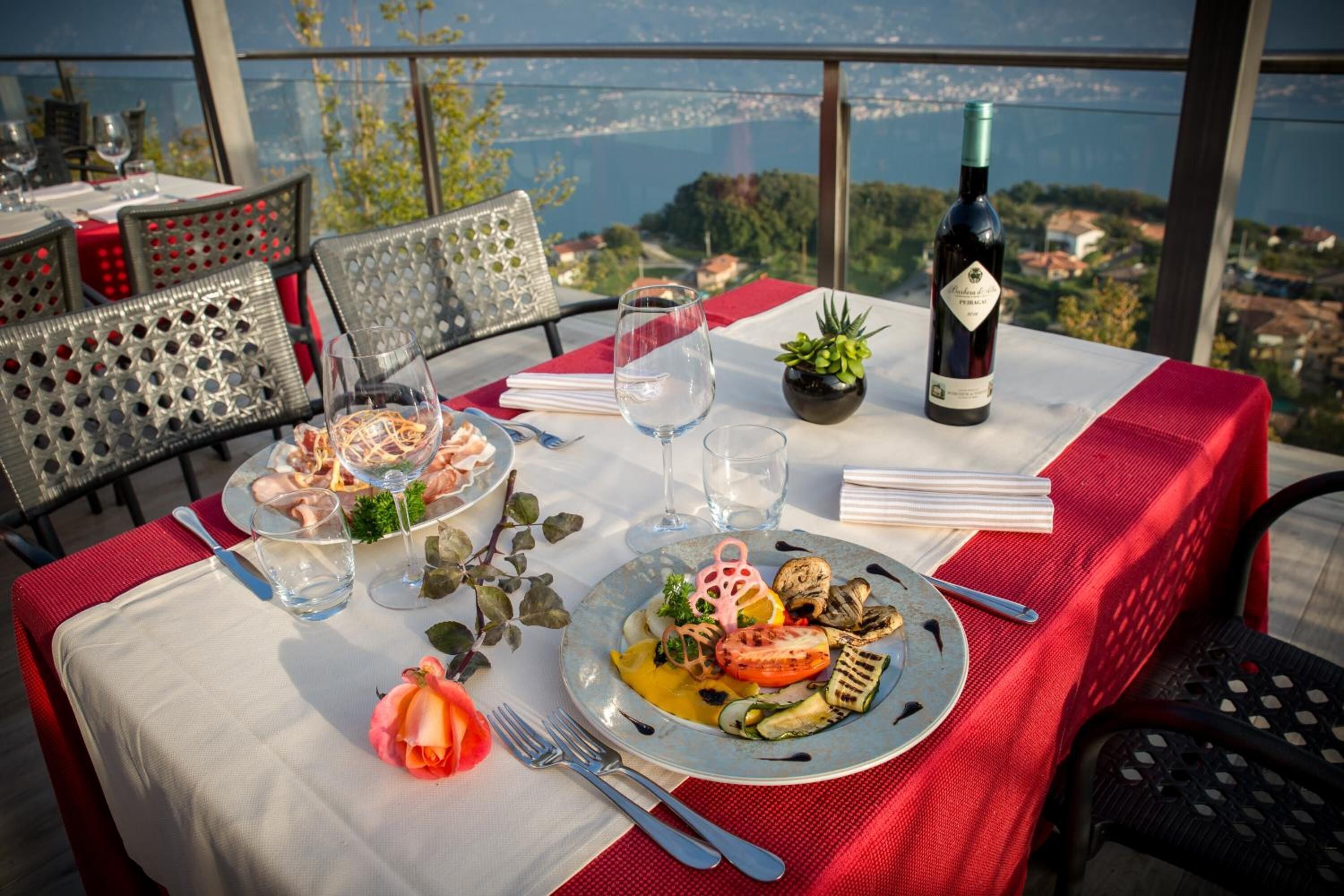 Une table dressée pour un repas, avec une vue panoramique, comprenant une bouteille de vin et une petite plante.