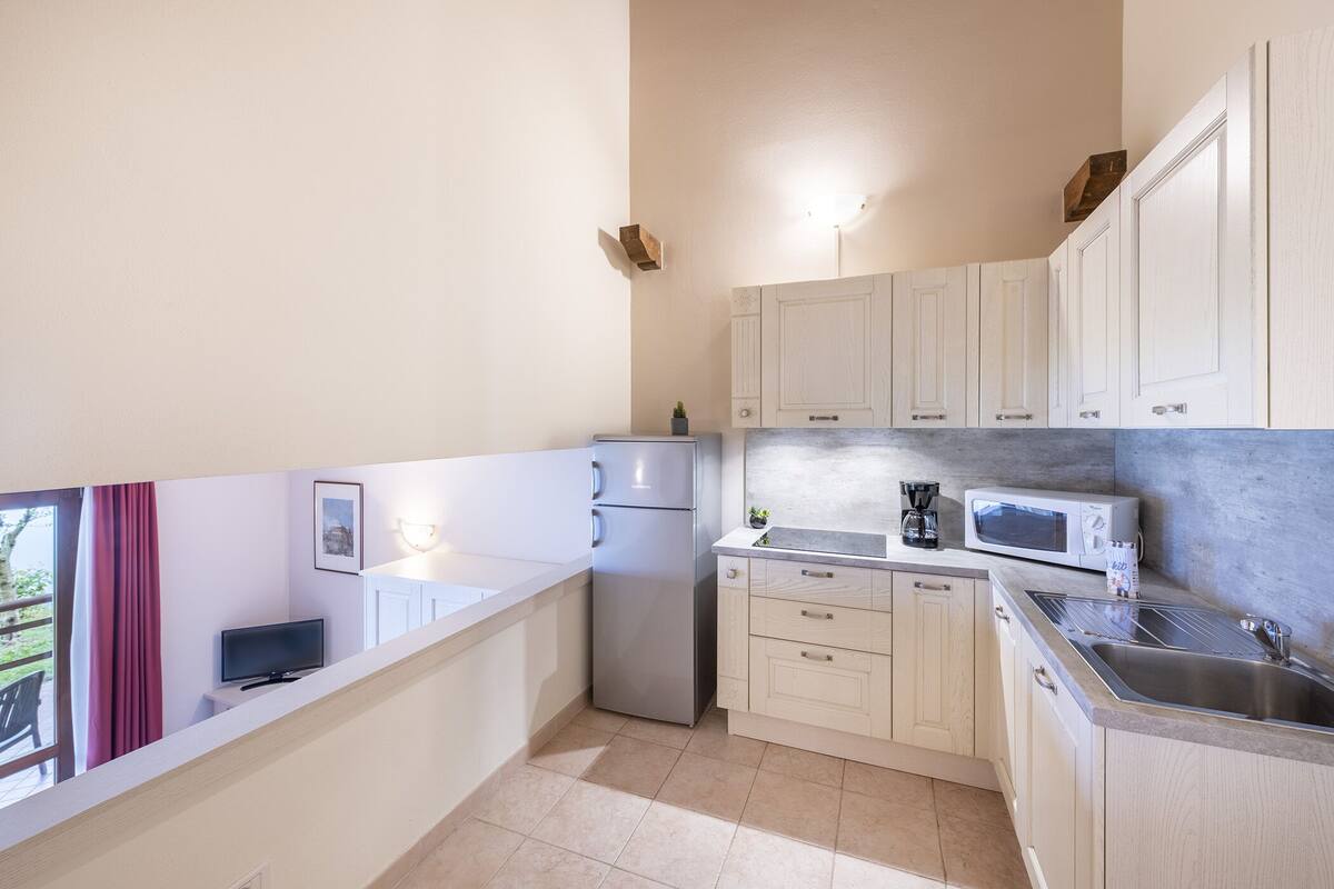 A modern kitchen with white cabinets, a stainless steel sink, a refrigerator, and a microwave.