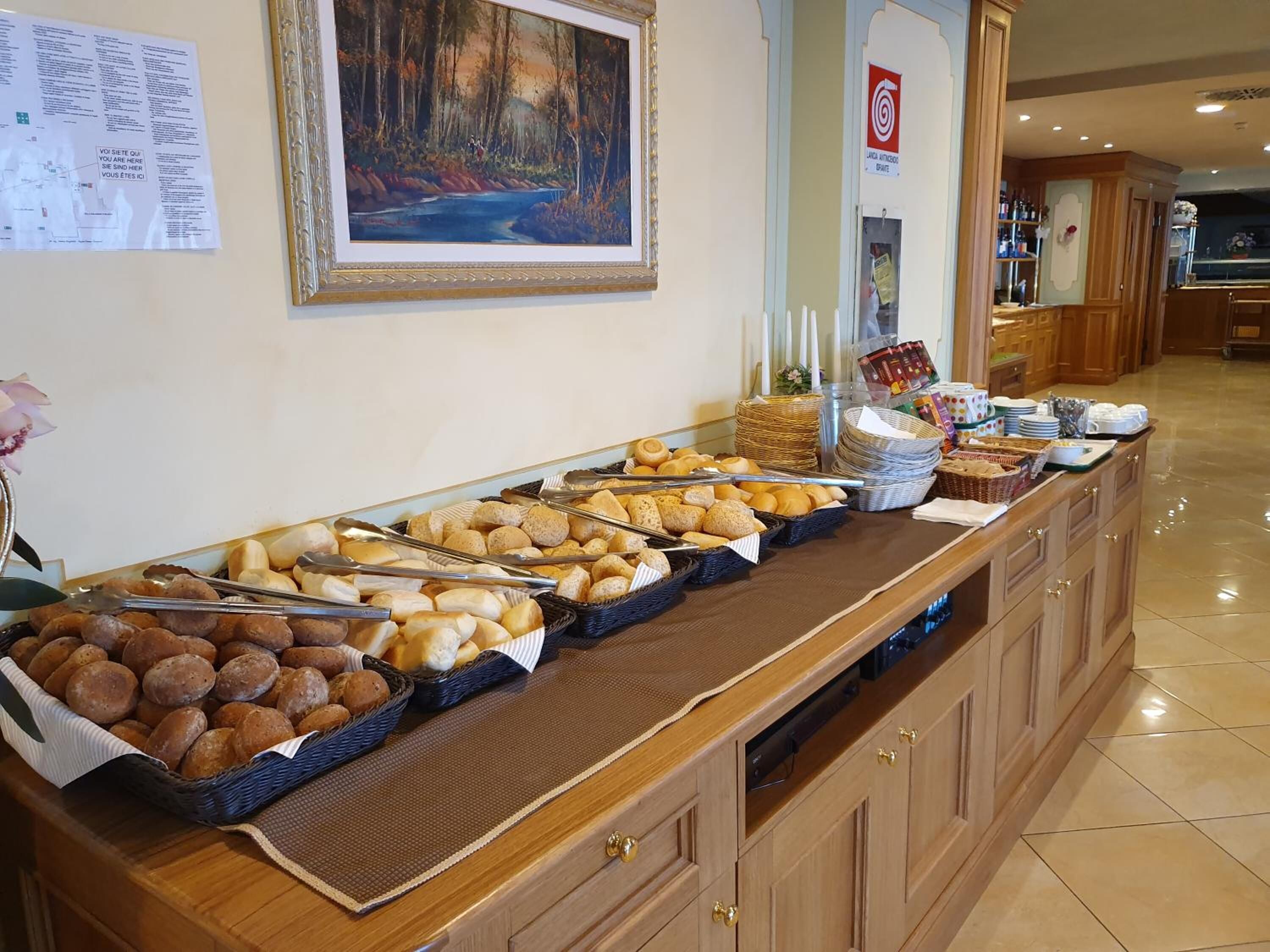 A buffet with various breads and pastries, a painting on the wall, and a sign with a target symbol.