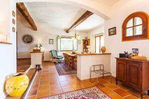 A spacious kitchen with a dining area, featuring a rustic wooden ceiling, a large island, and a view through an arched window. - VILLA ROCHE GRISE VI3010 by RIVIERA HOLIDAY HOMES (Berre-les-Alpes)