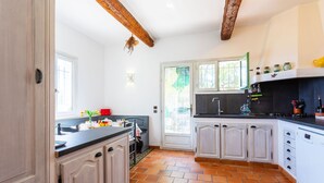 A kitchen with white cabinets, a black countertop, and a tiled floor. - VILLA ROCHE GRISE VI3010 by RIVIERA HOLIDAY HOMES (Berre-les-Alpes)