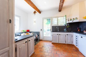 A kitchen with white cabinets, a black countertop, and a tiled floor. - VILLA ROCHE GRISE VI3010 by RIVIERA HOLIDAY HOMES (Berre-les-Alpes)