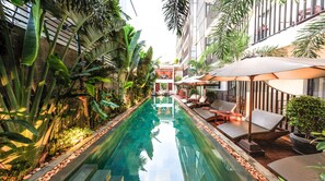 A serene indoor pool area with a clear view of the pool, surrounded by lush tropical plants and modern outdoor seating. - Sumeru Angkor Residence (Siem Reap)