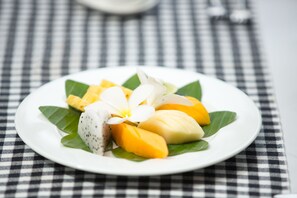 A plate of mango slices and a white flower on a checkered tablecloth. - Sumeru Angkor Residence (Siem Reap)