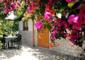 Un patio exterior con suelo de piedra, una puerta de madera y una mesa con sillas.