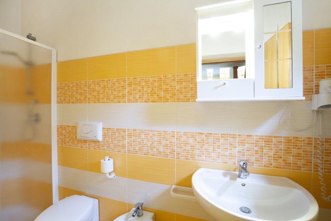Un baño con lavamanos blanco, inodoro y zona de ducha.