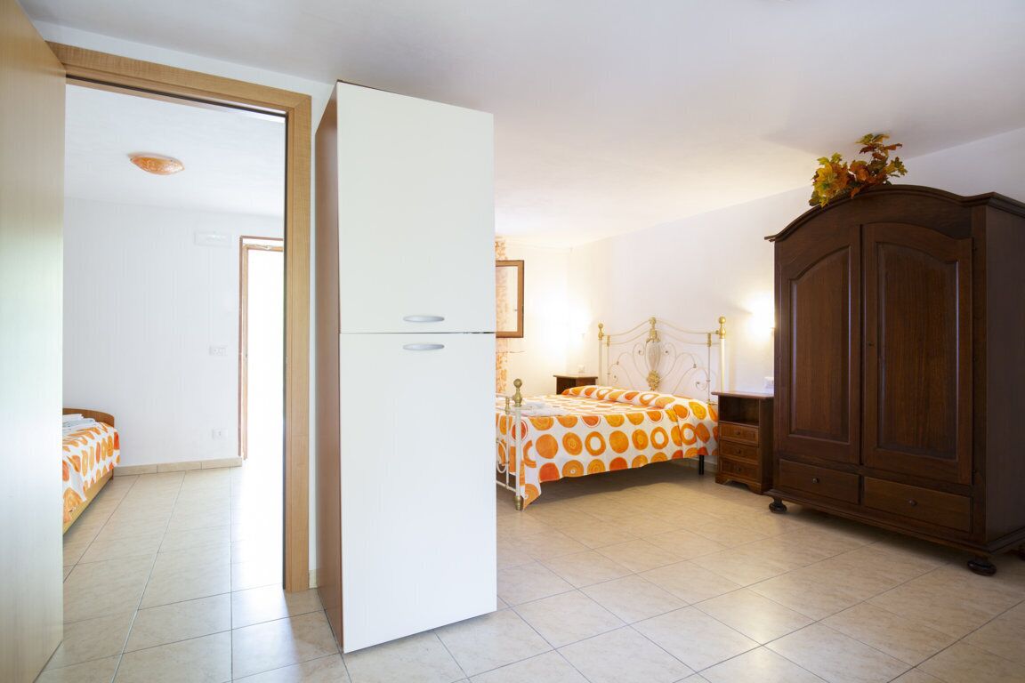 Een slaapkamer met een bed, een kledingkast en een deur naar een andere kamer.