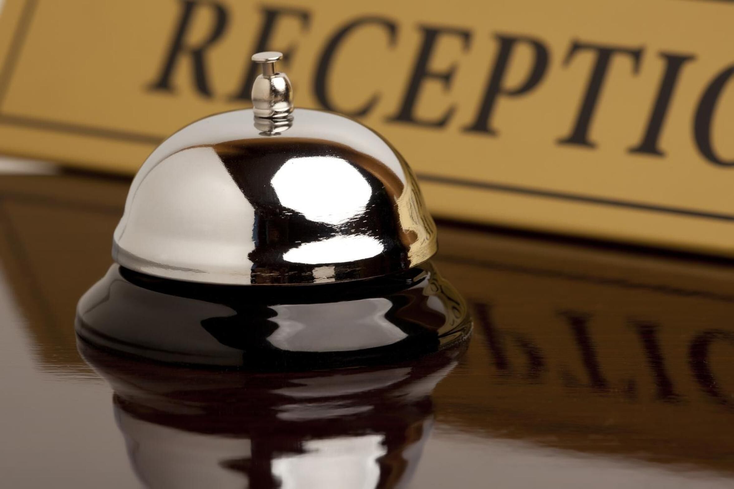A polished reception area with a reflective metal service bell and a sign that reads "RECEPTION".