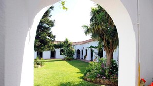 Un patio con un edificio blanco, césped verde y una palmera.