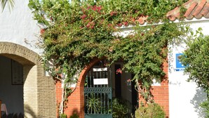 Un edificio blanco con un arco de ladrillo y una puerta verde con el rótulo "Capi".