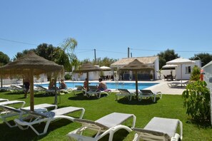 A poolside area with lounge chairs, umbrellas, and a swimming pool. - Hostal El Capi (Barbate)