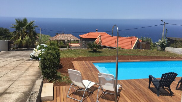 Una terraza de madera con piscina, dos sillas y un poste de metal.