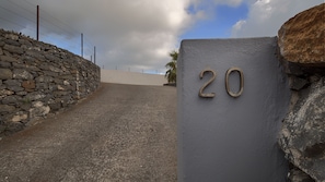 A stone wall, a paved path, and a building with the number 20 on it.