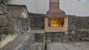 Una chimenea de piedra con detalles de ladrillo, ubicada frente a una pared de piedra y una pared blanca.
