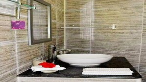 A bathroom with a large white sink, a mirror, and a towel rack. - La Nature Apartments (Mahé Island)
