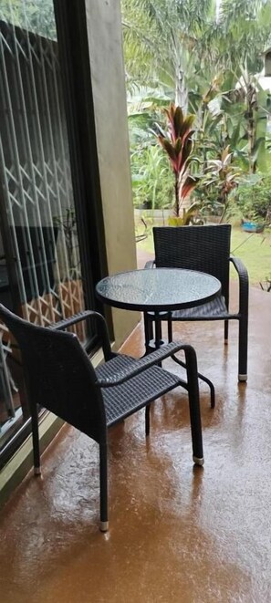 A covered outdoor seating area with a round table and two chairs.