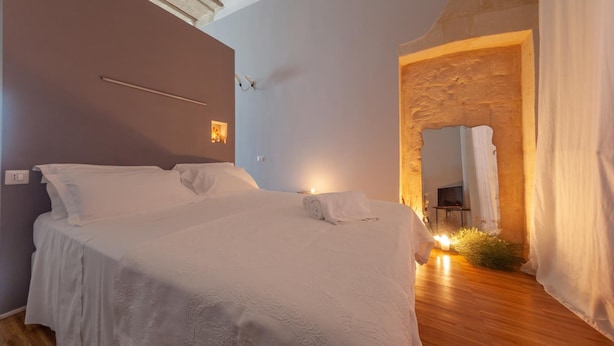 Ein Schlafzimmer mit einem großen Bett, einer Steinwand und einem Spiegel.
