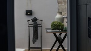 Ein modernes, minimalistisches Zimmer mit Holzboden, einer weißen Wand und einem kleinen Tisch mit einer Vase und einer Pflanze.