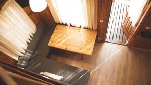 Interior de una cabaña de madera con sofá, mesa y lámpara colgante.