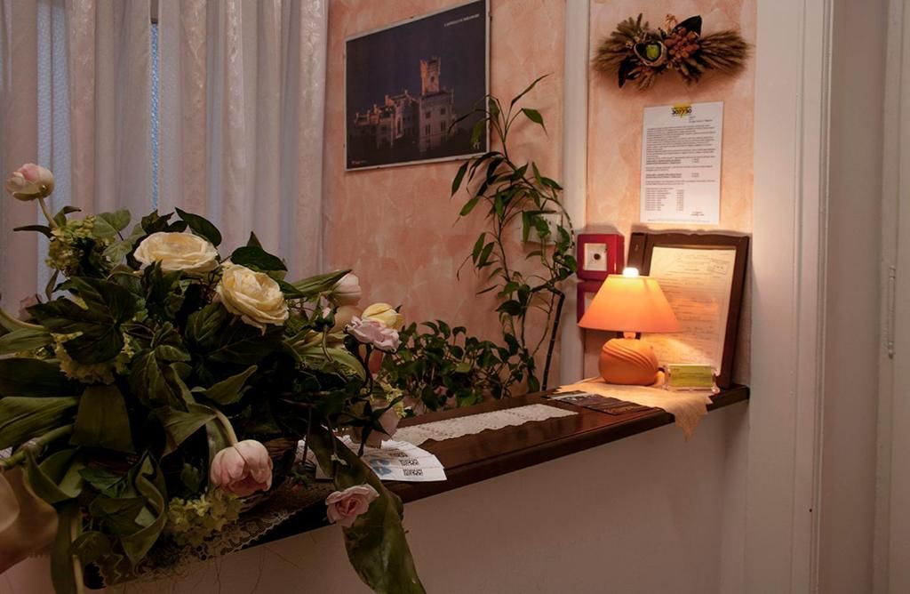Un mostrador de recepción con un florero, una lámpara y un cuadro en la pared.