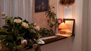A reception desk with a vase of flowers, a lamp, and a framed picture on the wall. - Affittacamere Berzi (Trieste)