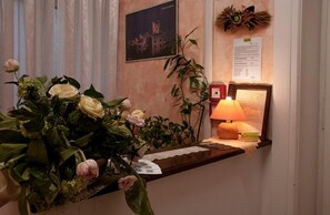 Un mostrador de recepción con un florero, una lámpara y un cuadro en la pared.