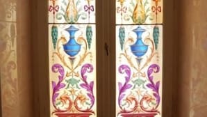 A stained glass window with symmetrical floral and geometric patterns. - Affittacamere Berzi (Trieste)