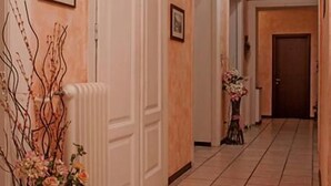 A hallway with white doors, a radiator, and a vase with flowers. - Affittacamere Berzi (Trieste)