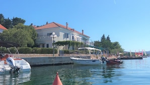 Un port de plaisance avec des bateaux amarrés, un bâtiment doté d’un toit recouvert de tuiles rouges et un ciel d’un bleu limpide.