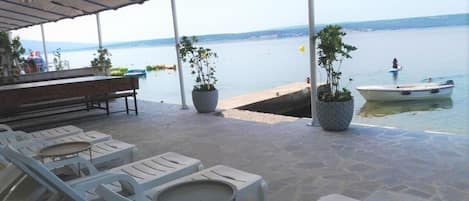 Un espacio de estar al aire libre cubierto con sillones de descanso, mesas, un bar y vistas al agua.
