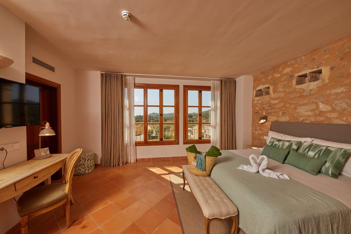 A hotel room with a bed, a desk, a chair, a television, and a window with a view.