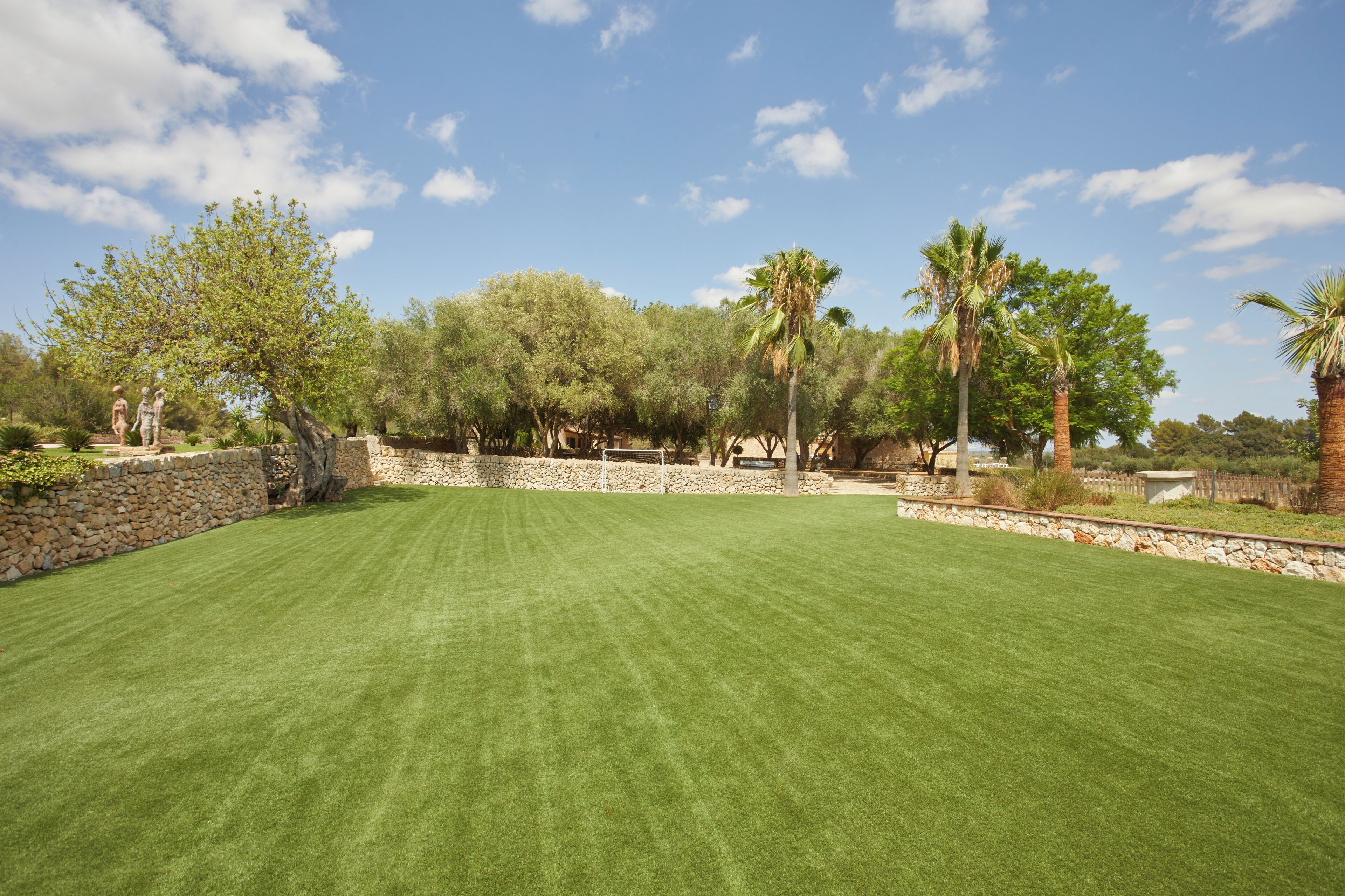 A well-maintained lawn with stone walls and trees, likely part of a resort or hotel property.