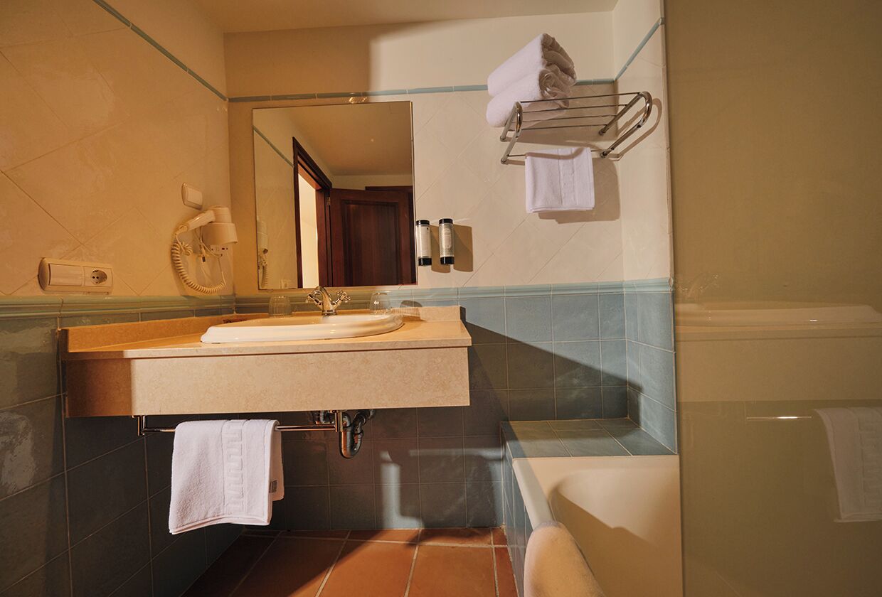 Une salle de bain équipée d’un lavabo, d’un miroir, d’un porte-serviettes et d’une baignoire.