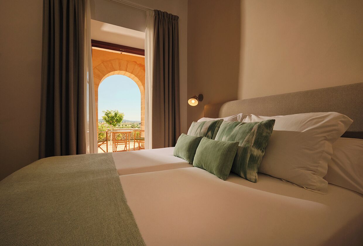 Habitación de hotel con cama, vistas a un espacio exterior y balcón.