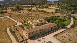 An aerial view of a building with a courtyard, surrounded by fields and a road.