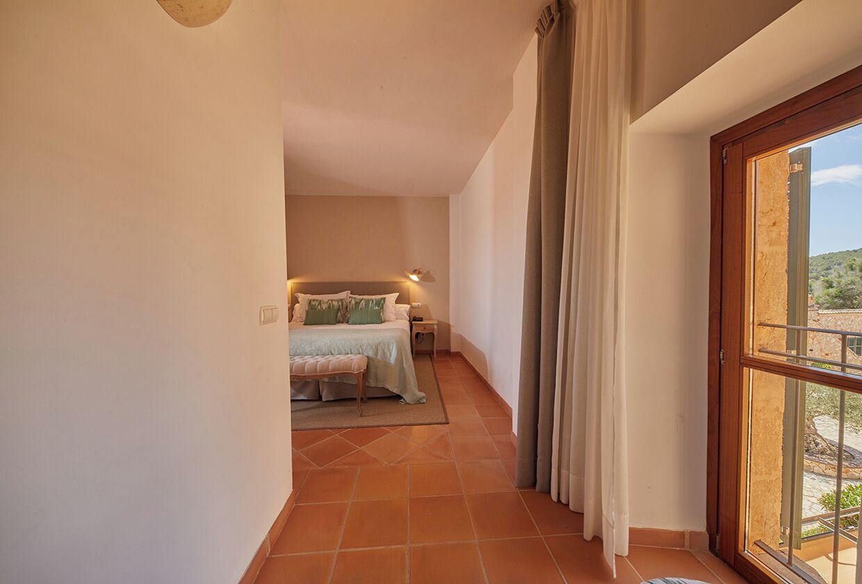 Ein Schlafzimmer mit Bett, Nachttisch und Blick durch ein Fenster.