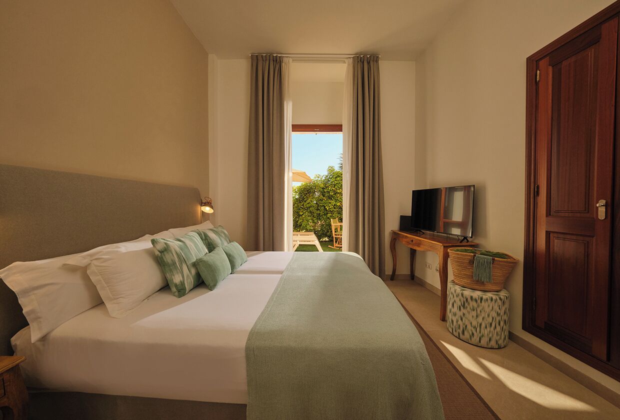 A hotel room with a bed, a television, a desk, and a view of the outdoors.