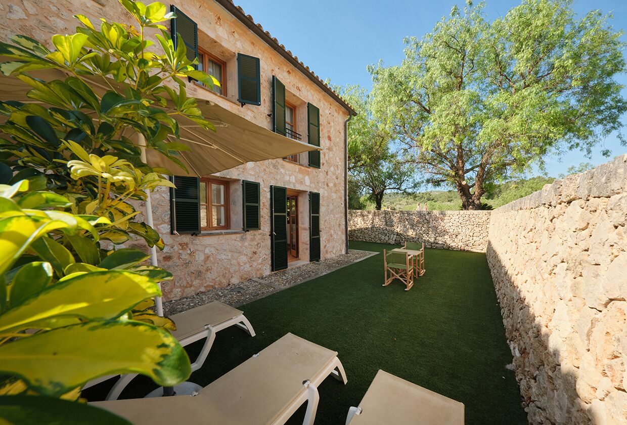 A stone building with a balcony, outdoor seating, and a tree.